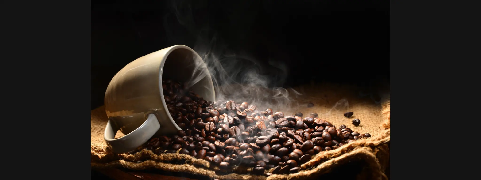 Imagem xícara com grãos de café quente derramando sobre tecido de saco